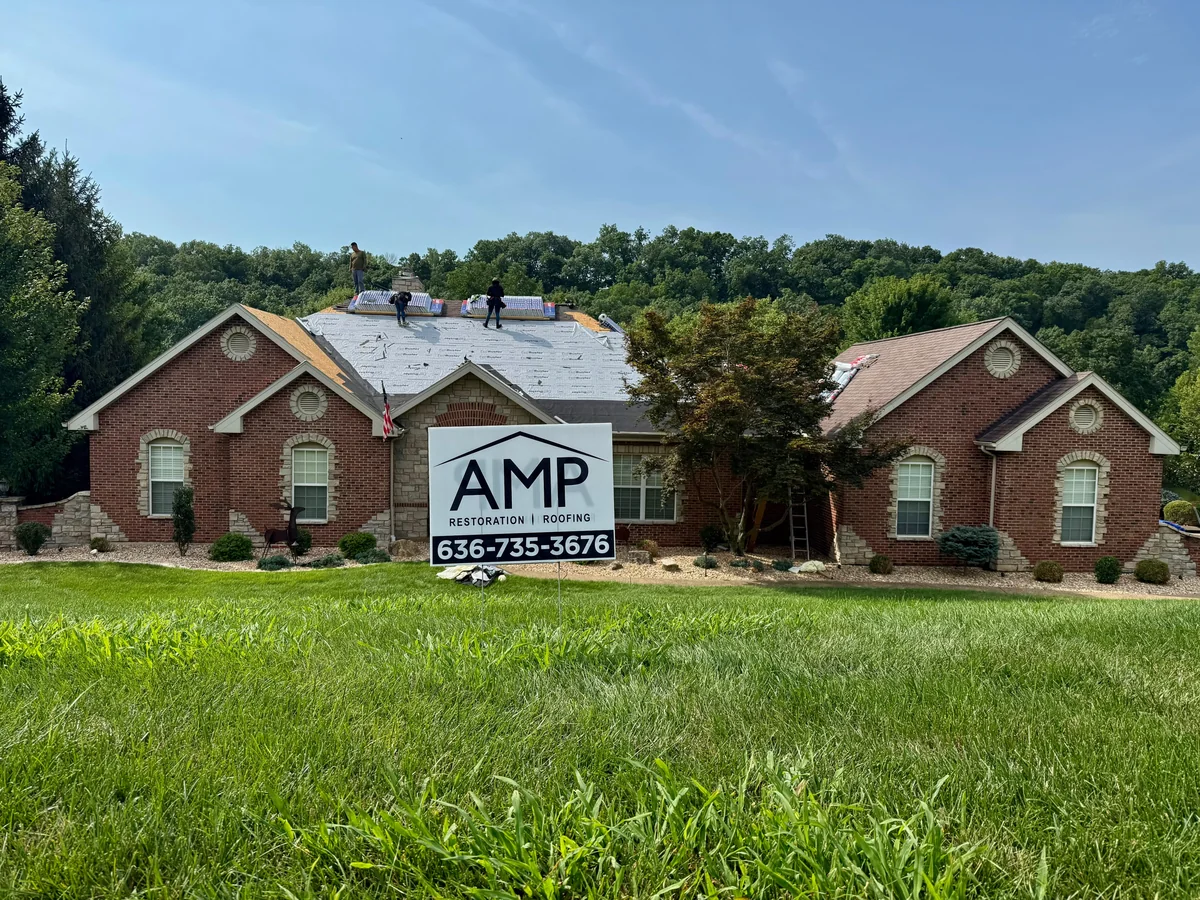 AMP roof installation in progress with underlayment, exposed decking, and shingle bundles visible